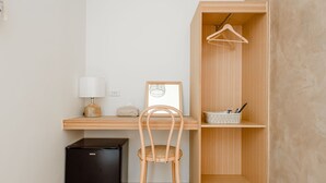 A compact room with a wooden desk, a black refrigerator, a chair, a hanging light, a framed picture, and a wooden wardrobe with a hanging rack. - Apple Scent Easy Stay (Magong)