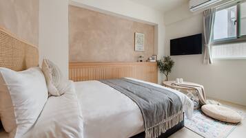 A modern bedroom with a bed, bedside table, air conditioning unit, and a window with curtains.
