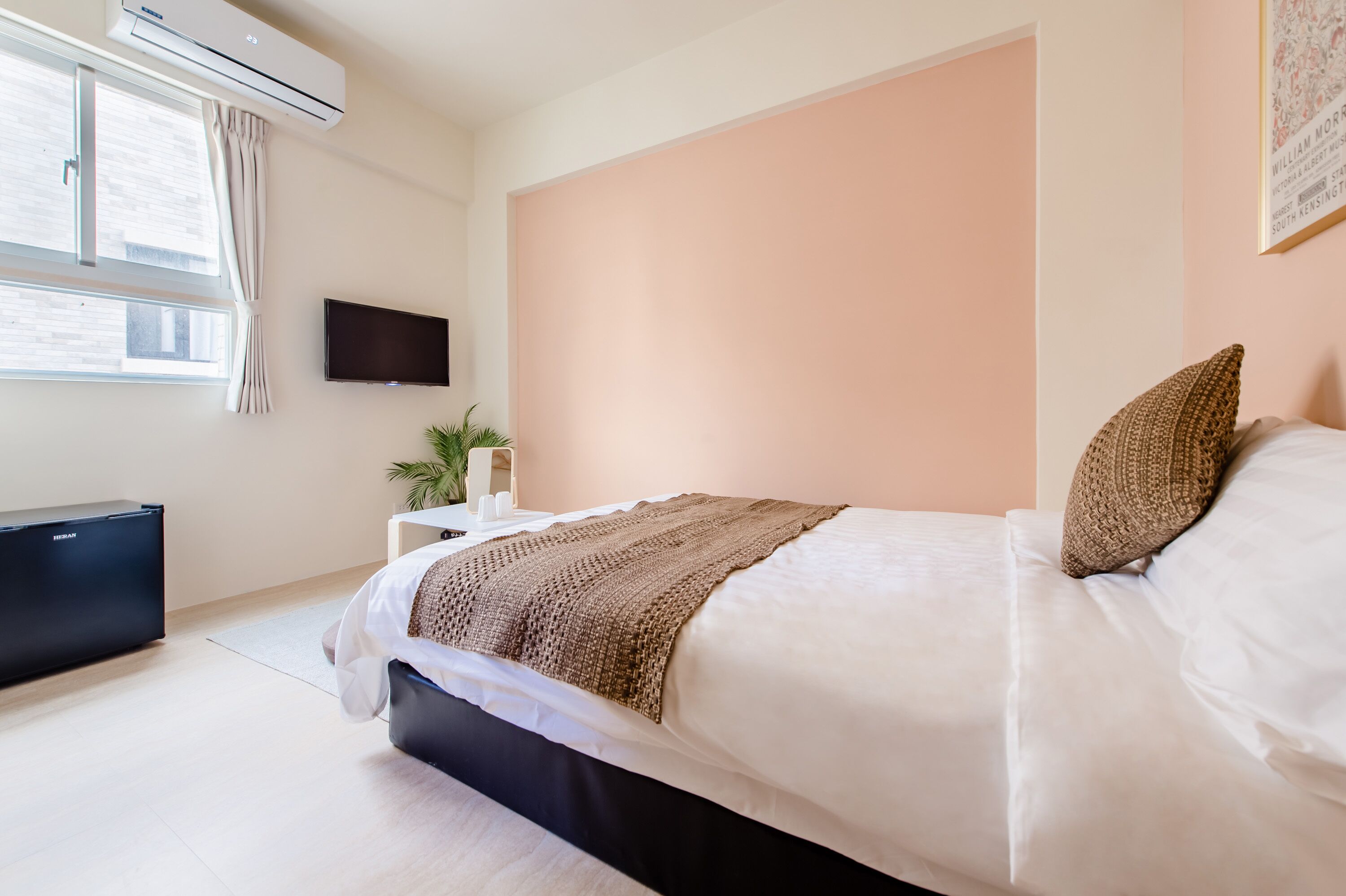A bedroom with a bed, a TV, an air conditioner, and a window.