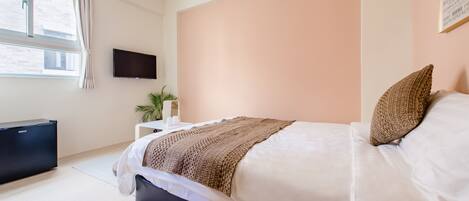 A bedroom with a bed, a TV, an air conditioner, and a window.