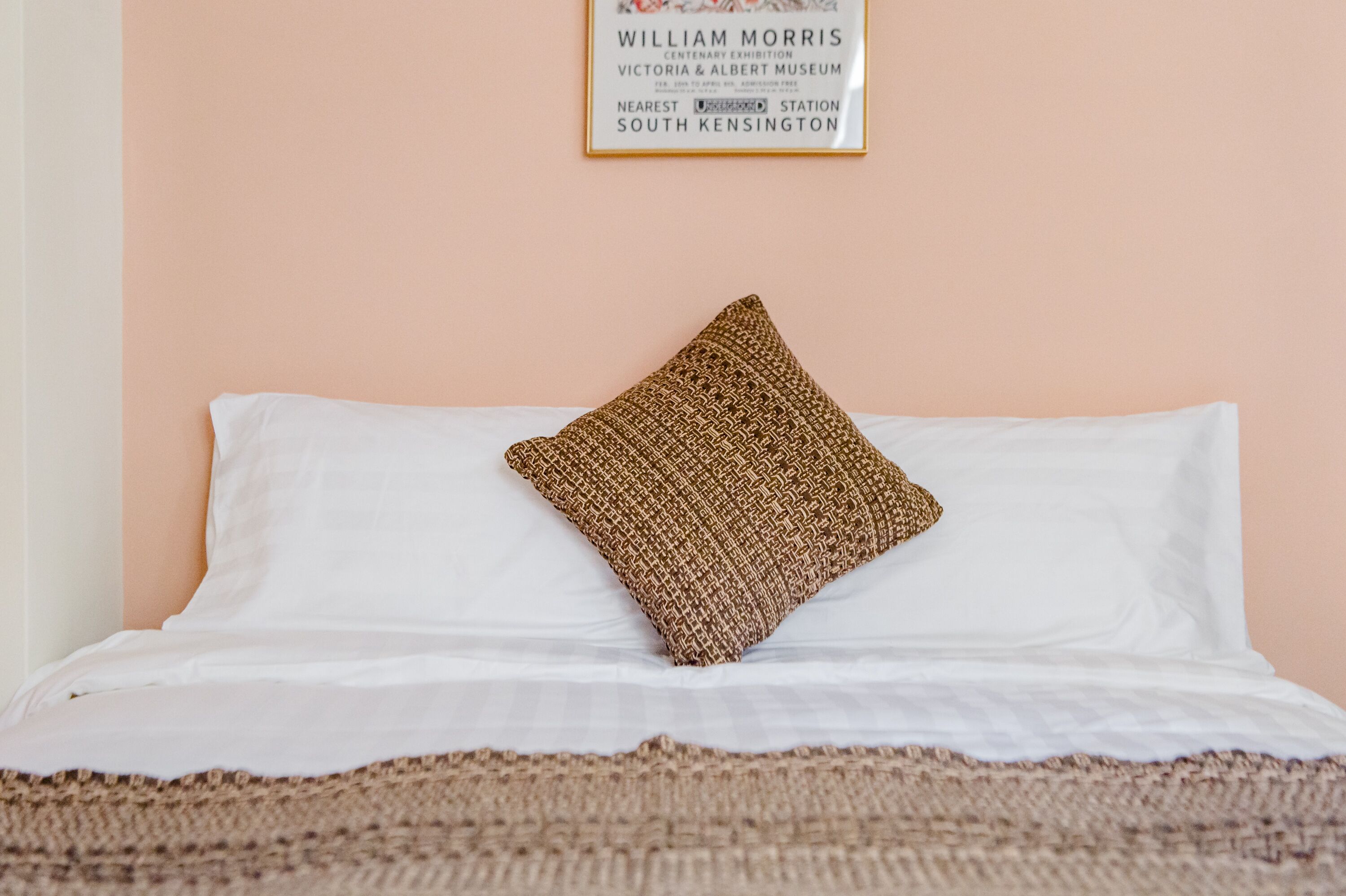 A bed with a white sheet and a textured brown pillow.