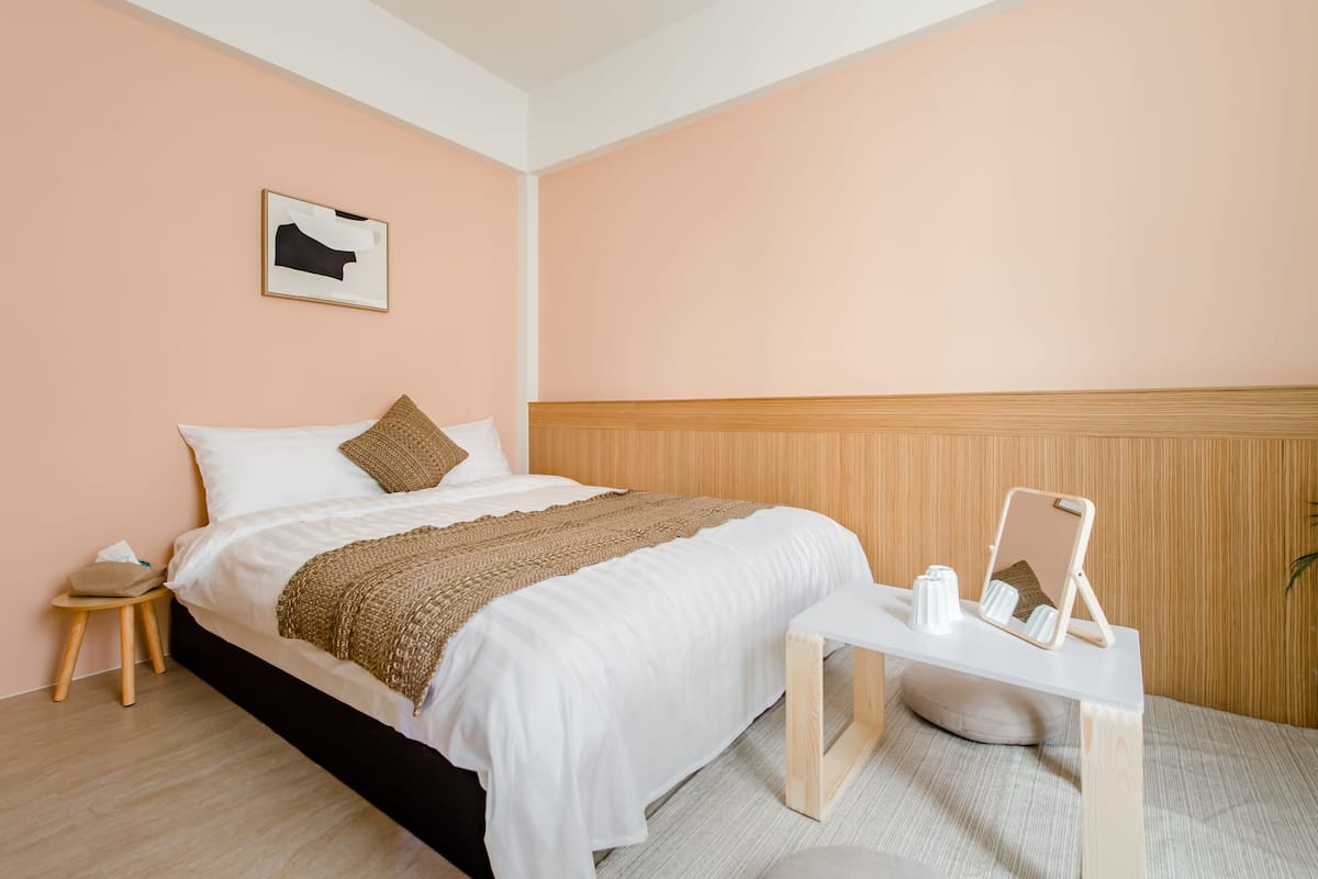 Un dormitorio ordenado con cama, mesita de noche y un cuadro enmarcado en la pared.
