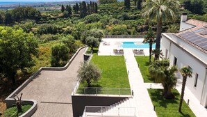 En moderne villa med swimmingpool, velplejet have og udsigt over det omkringliggende landskab.