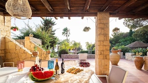 An outdoor dining area with stone walls, potted plants, and a view of the surrounding landscape.