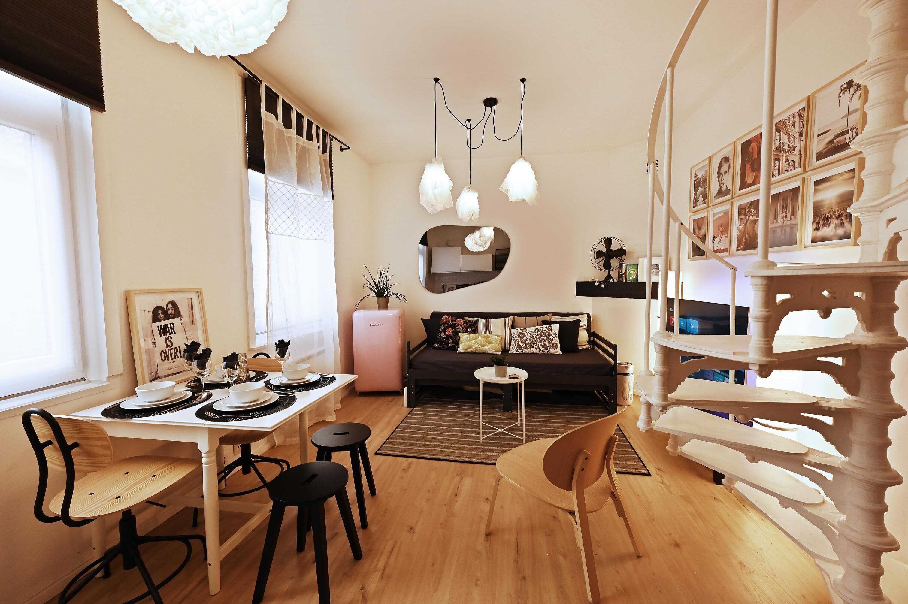 Een moderne woonkamer met een eethoek, een bank, een bijzettafeltje en een decoratieve spiegel.