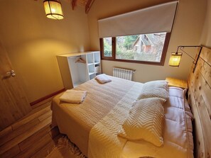 Une chambre à coucher avec un grand lit, une armoire, un radiateur et une fenêtre donnant sur une maison.