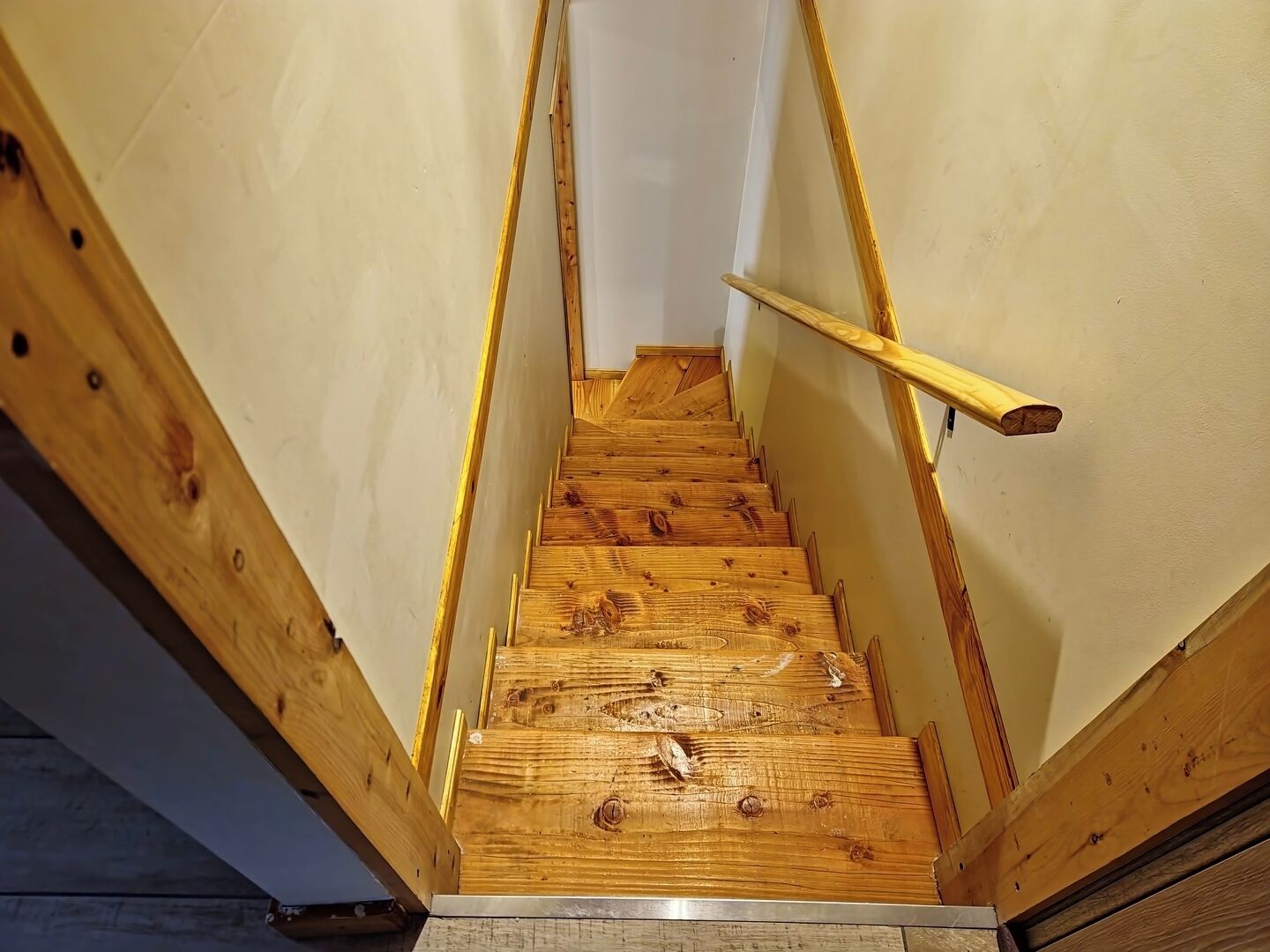 Un escalier en bois, doté d’une rampe, menant à l’étage supérieur.