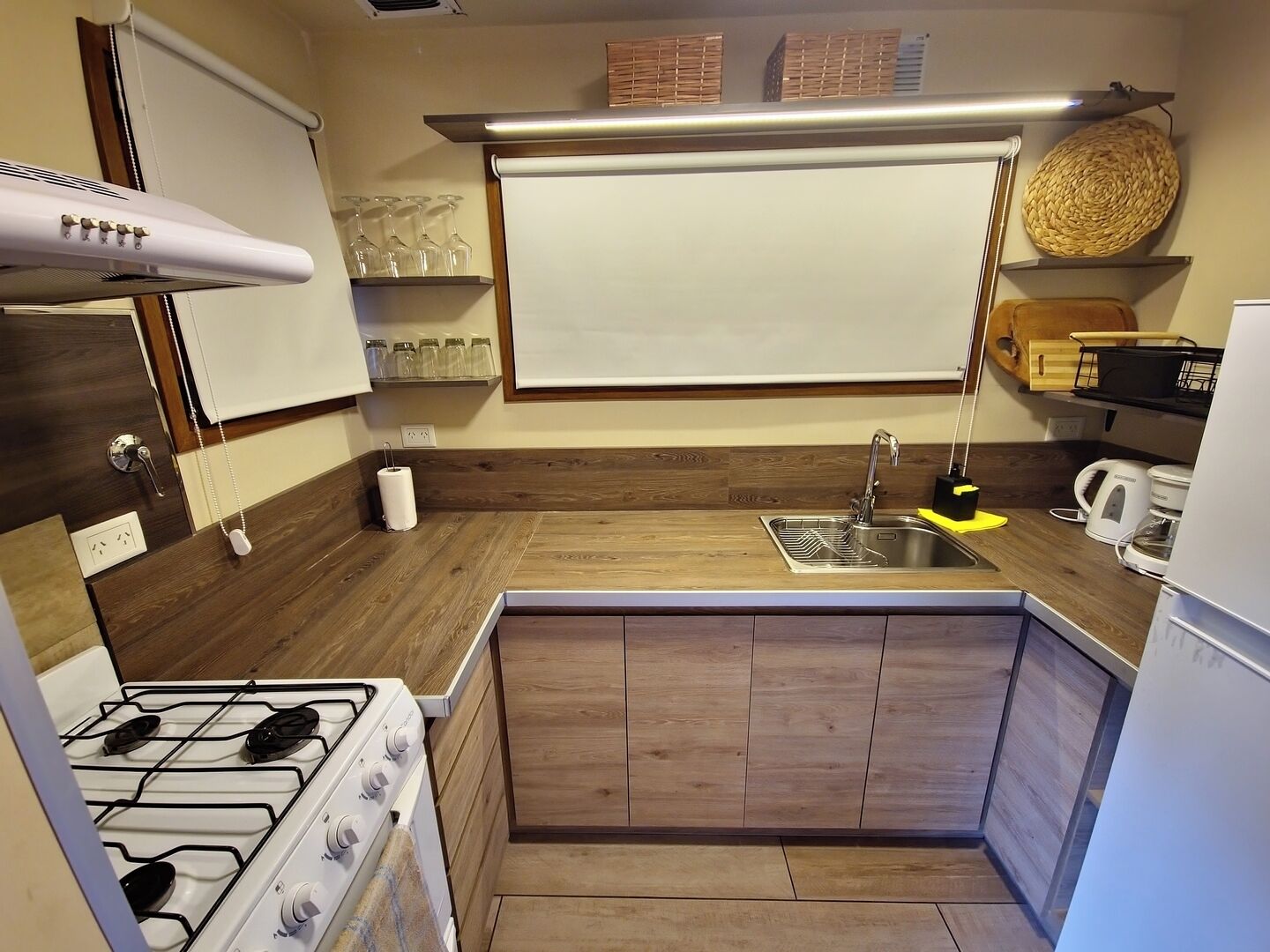 A compact kitchen with a gas stove, a sink, and wooden cabinetry.