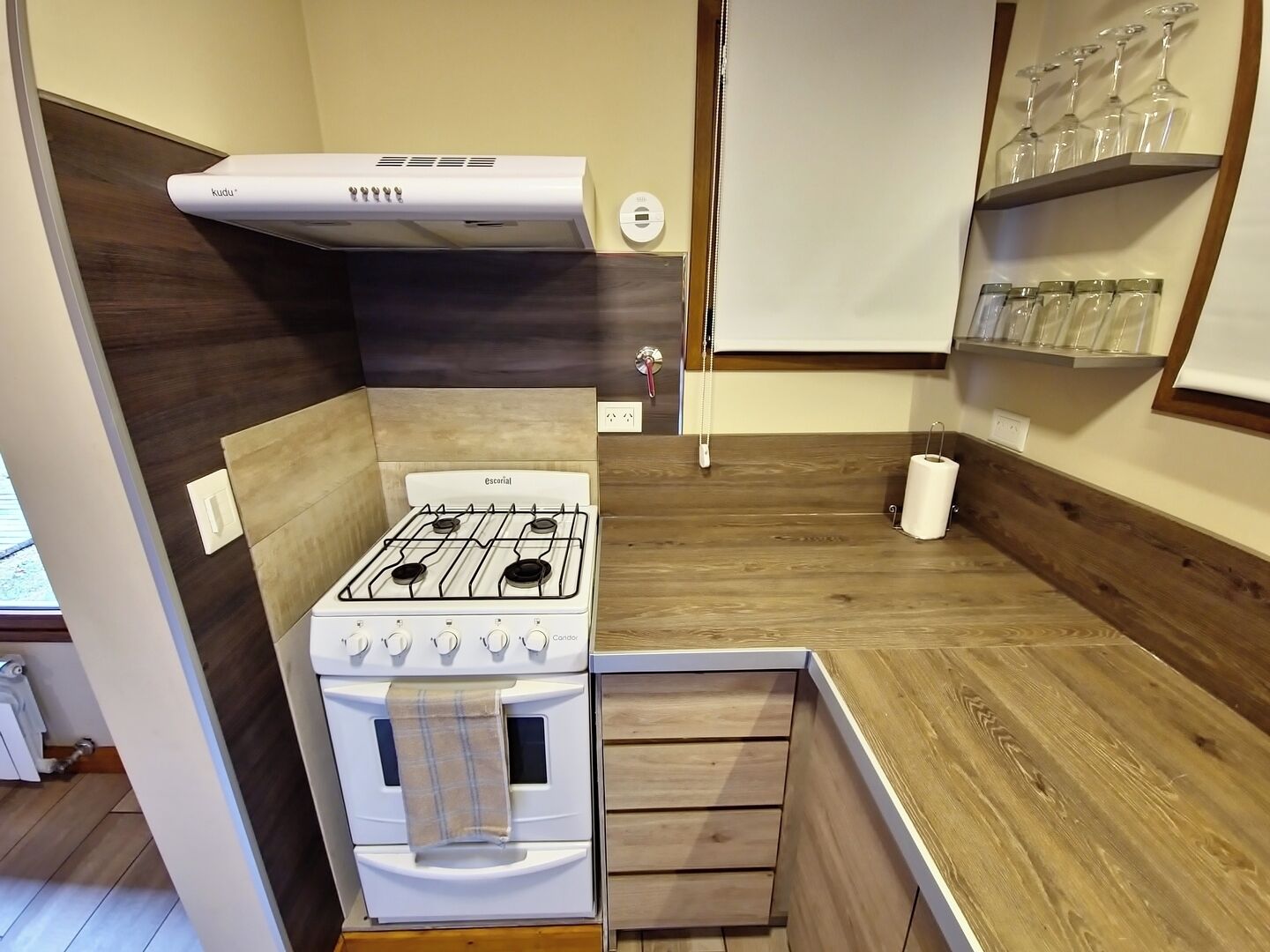 A compact kitchen with a gas stove, oven, and wooden cabinetry.