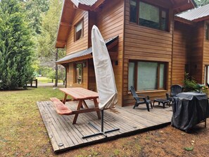 Une cabane en bois dotée d’une terrasse, d’une table de pique-nique et d’un espace salon extérieur.