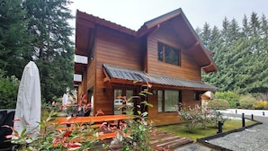 Een houten chalet met terras, omgeven door groen en bomen.