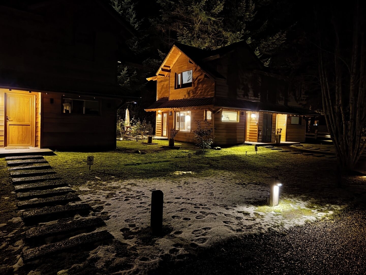 Una cabaña de madera con una entrada bien iluminada y un pequeño porche.