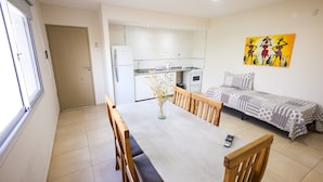 A compact living space with a dining area, kitchenette, and a bed.