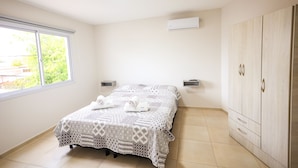 A bedroom with a bed, two bedside tables, a wardrobe, and a window.