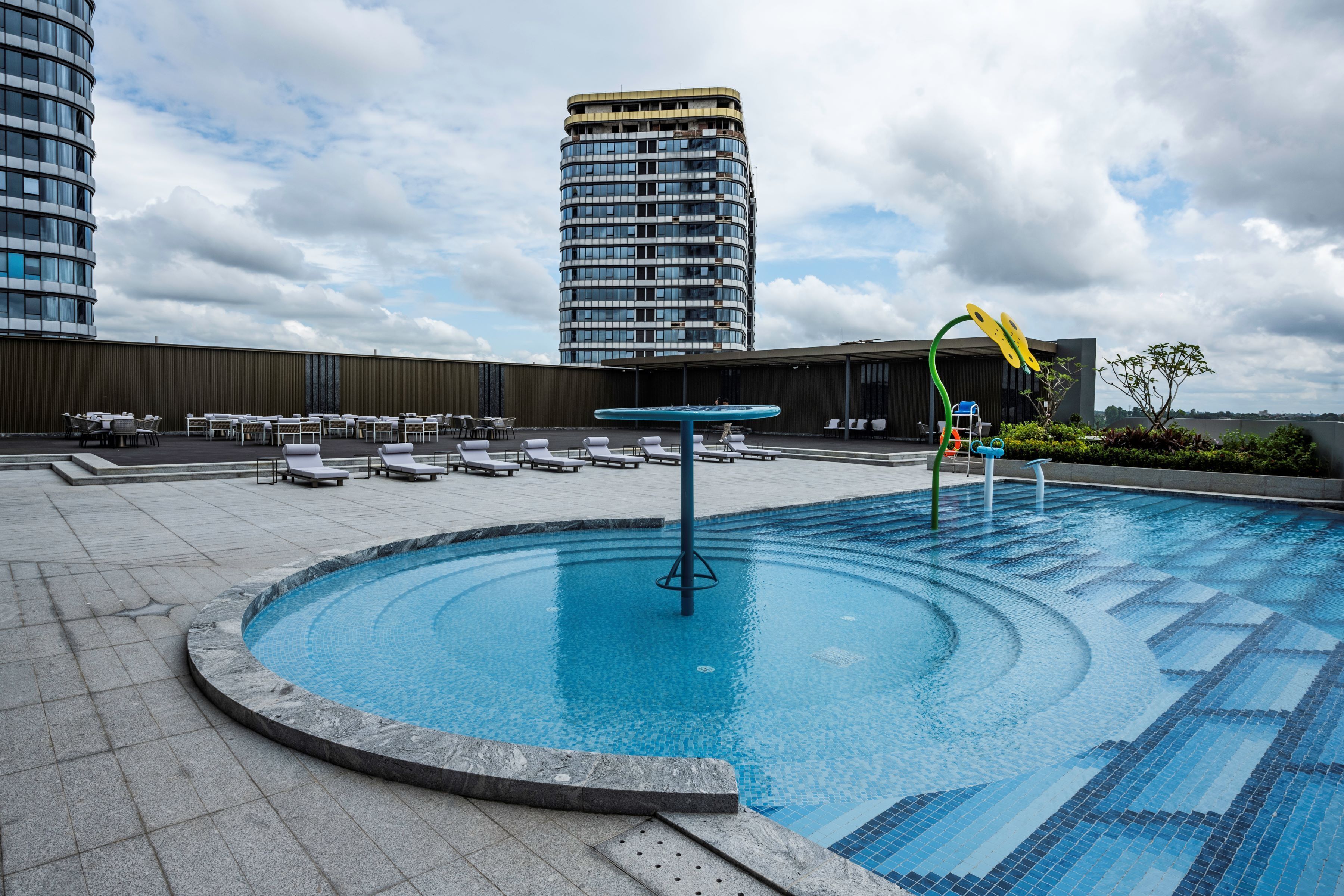 A rooftop swimming pool with lounge chairs and a view of a tall building.