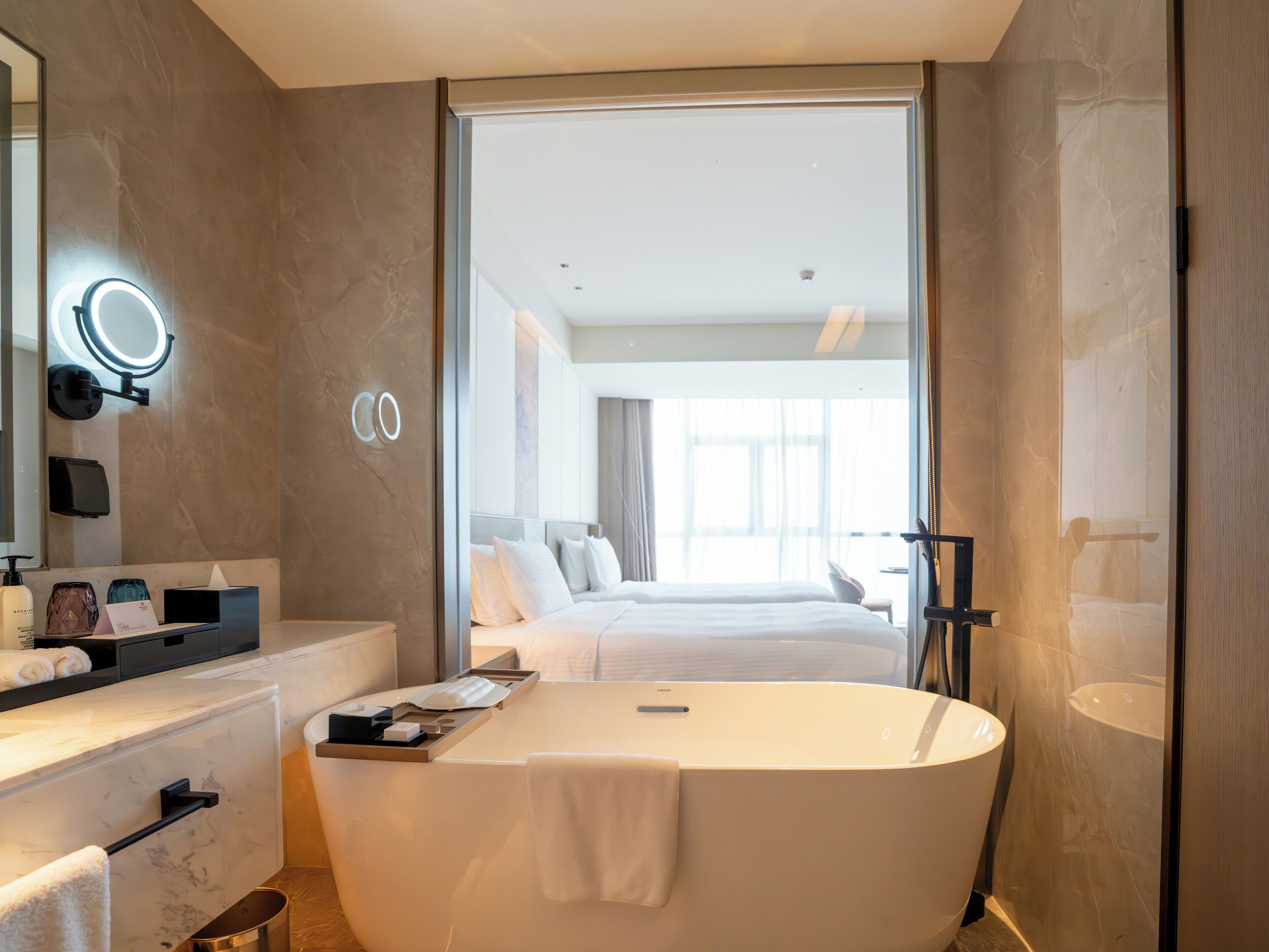 A modern bathroom with a freestanding bathtub, a vanity with a mirror, and a large window providing natural light.