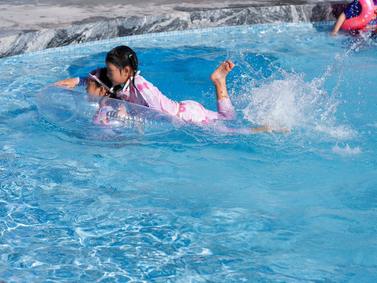 A person in a swimming pool with a clear water surface and a tiled edge.