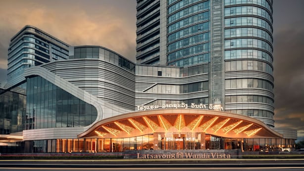 A modern hotel with a curved facade, large glass windows, and a prominent entrance with illuminated signage.