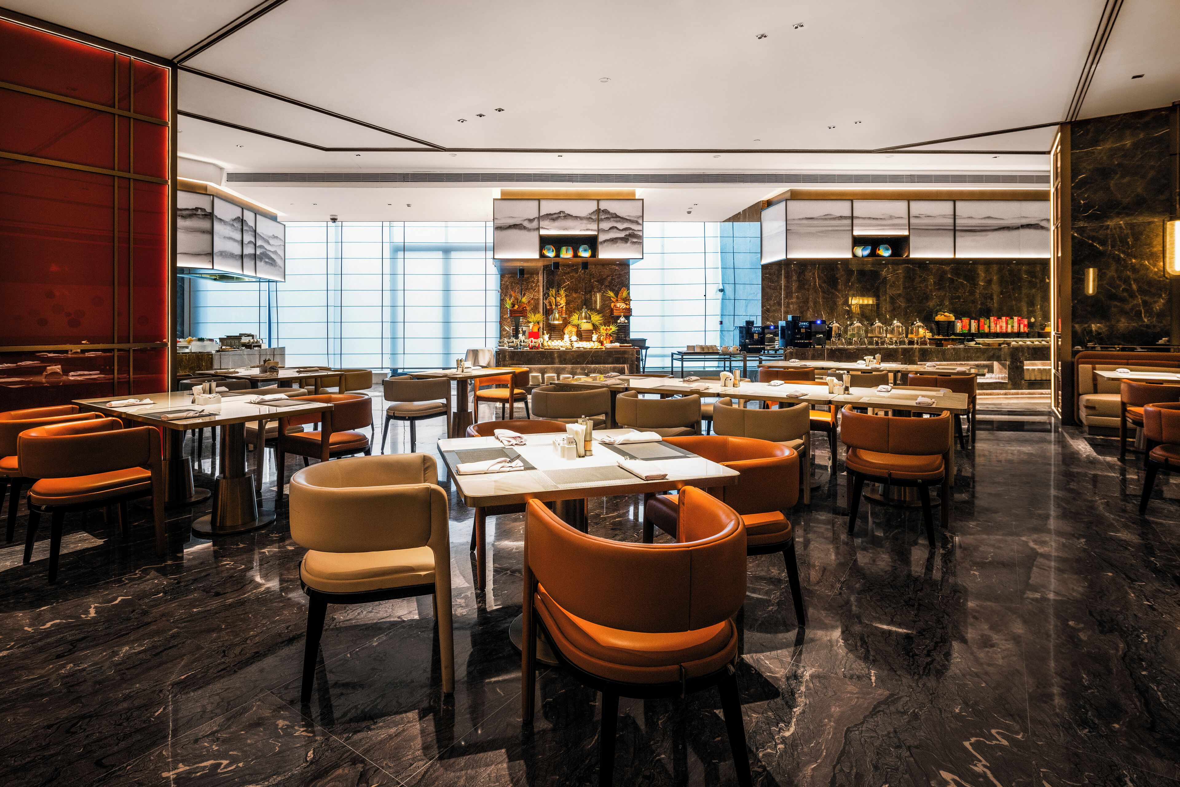 A modern restaurant with marble flooring, orange and beige chairs, and a central bar area.