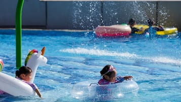 Swimmers can enjoy the pool's clear blue water, surrounded by a roofed area.