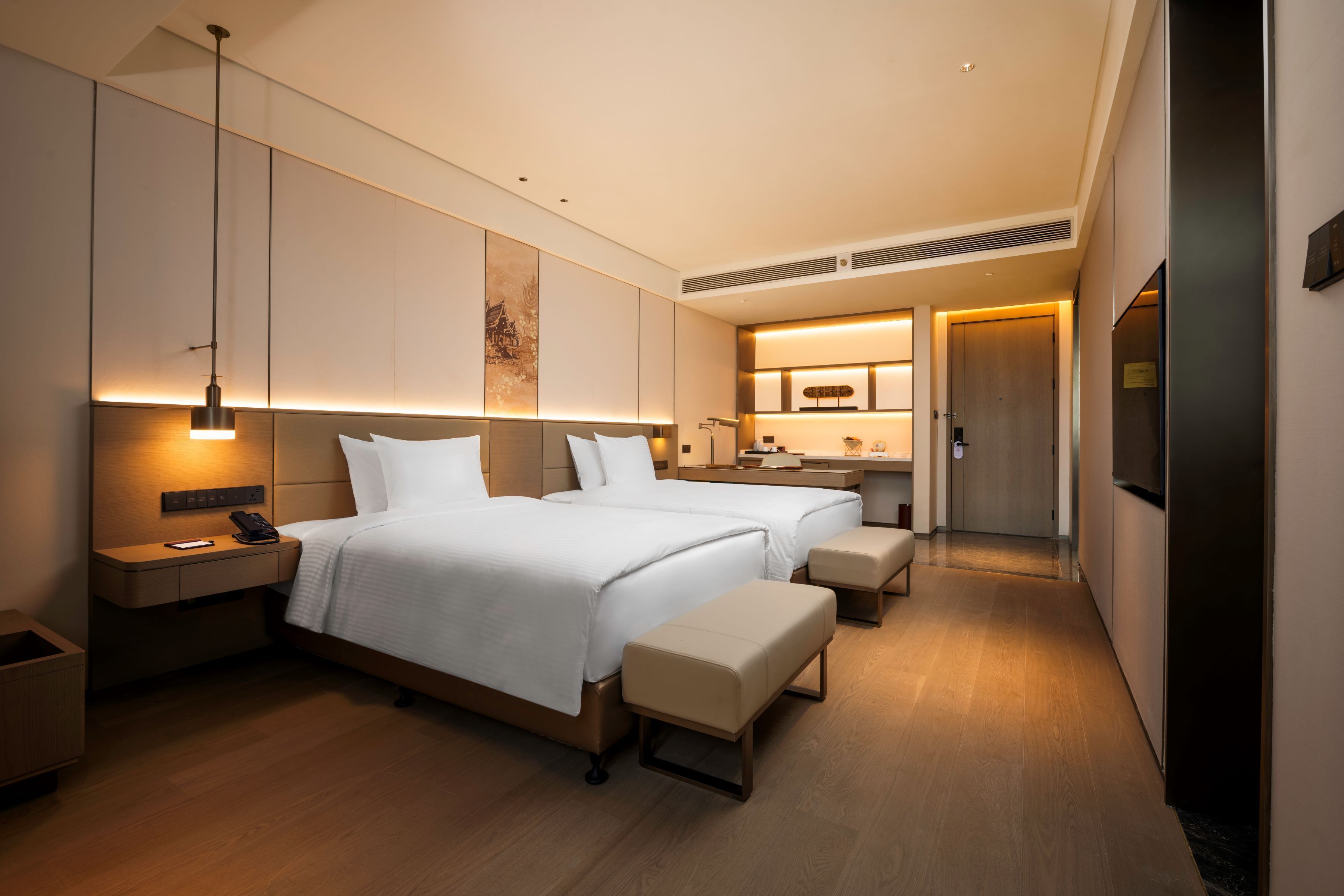Ein modernes Hotelzimmer mit einem großen Bett, Nachttischen, einem Schreibtisch und einer Küchenzeile.
