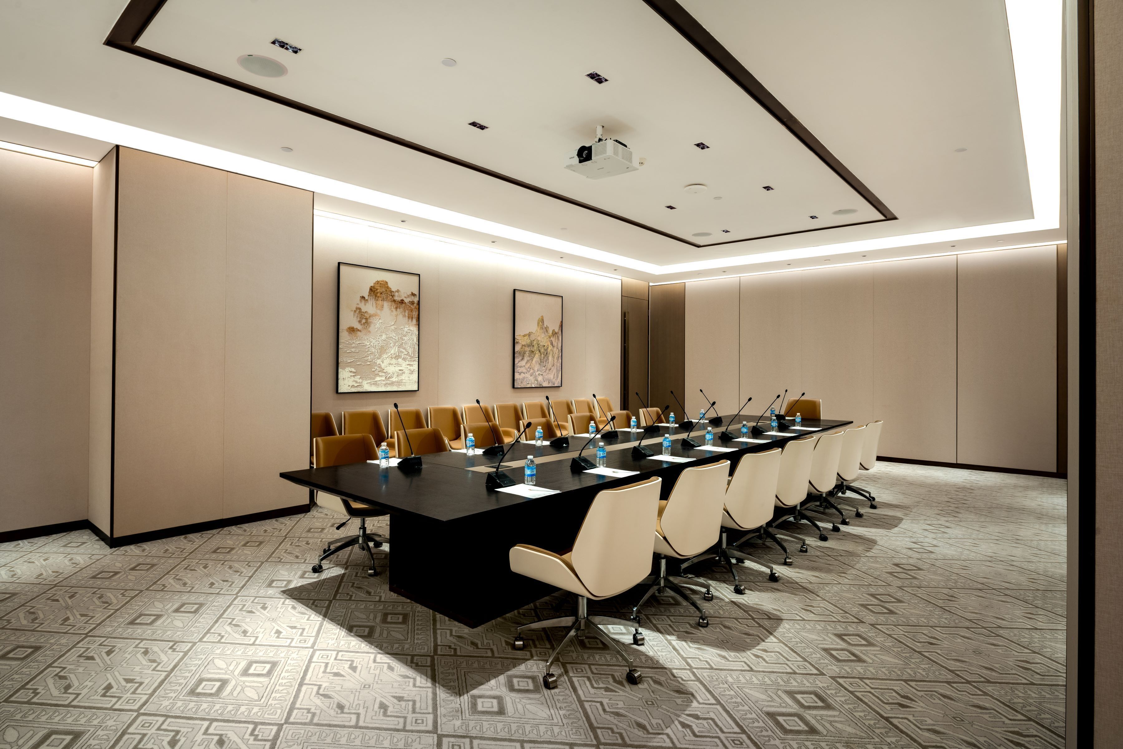 Een vergaderzaal met een lange tafel, stoelen en een plafond met inbouwspots.