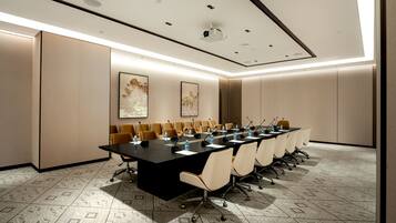 Een vergaderzaal met een lange tafel, stoelen en een plafond met inbouwspots.
