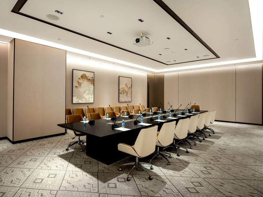Een vergaderzaal met een lange tafel, stoelen en een plafond met inbouwspots.
