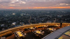 Restaurante en la azotea con mesas al aire libre y vistas a un paisaje urbano al anochecer.
