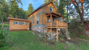 A wooden cabin with a stone foundation, a balcony, and a separate smaller cabin. - Cozy cabin in the woods, minutes from town, beaches, hiking (Eastsound)