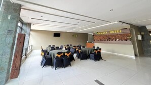 A hotel lobby with a reception desk, a seating area with tables and chairs, and a stone wall on the left. - Ommaya Hotel & Resort (Baki)