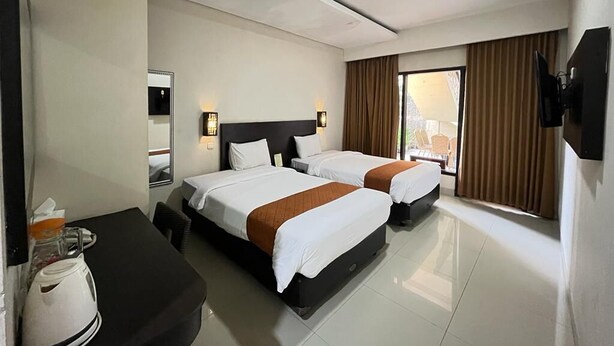 A hotel room with two beds, a desk with a coffee maker, and a TV mounted on the wall. - Ommaya Hotel & Resort (Baki)