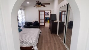 A bedroom with a bed, a ceiling fan, a TV, and a desk. - A tropical paradise in the desert! (Cathedral City)