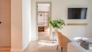 A modern living room with a wooden floor, a sofa, a coffee table, a TV mounted on the wall, and a staircase leading to another room. - HommyHome Duque de Veragua 101 (Sevilla)