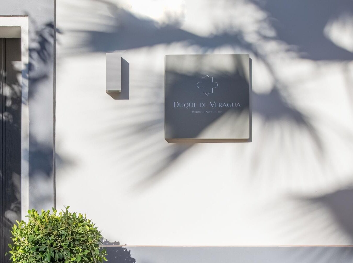A sign for 'Quai de Veragua Boutique Apartments' mounted on a wall with a minimalist design.