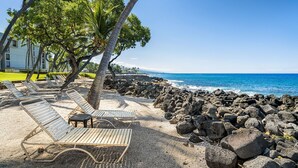 A beach with lounge chairs and a rocky shoreline. - 🏖️Partial Ocean View Condo w/ A/C | Kona Isle B25 (Kailua Kona)