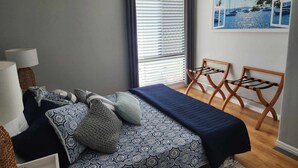 Un dormitorio con cama, escritorio, silla y ventana con persianas.