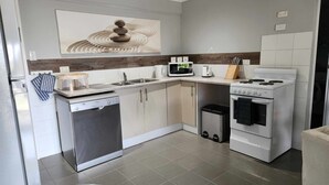 Una cocina moderna equipada con lavavajillas, microondas, estufa y pileta.