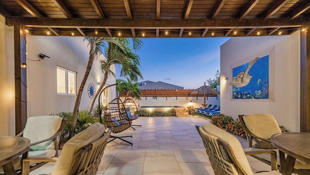 An outdoor patio with wicker chairs and tables, a thatched roof, and a painting of a fish. - 3BR 2BA Near Eagle Beach w/ Private Pool (Noord)