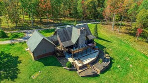 A large, multi-story log cabin with a deck and outdoor seating area. - Wow! Timber Ranch Lodge, 43 acres, Sleeps 12, Family and Pet Friendly!  (Logan)