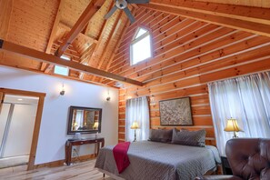 Un dormitorio con techo de madera, una cama, un escritorio y una silla.