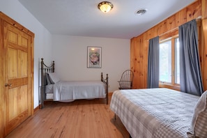 A room with two beds, wooden walls, a ceiling light, and a window with curtains. - Wow! Timber Ranch Lodge, 43 acres, Sleeps 12, Family and Pet Friendly!  (Logan)