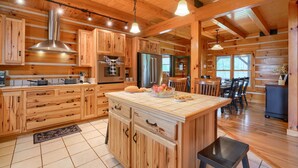 A spacious kitchen with wooden cabinetry, a central island, and modern appliances. - Wow! Timber Ranch Lodge, 43 acres, Sleeps 12, Family and Pet Friendly!  (Logan)