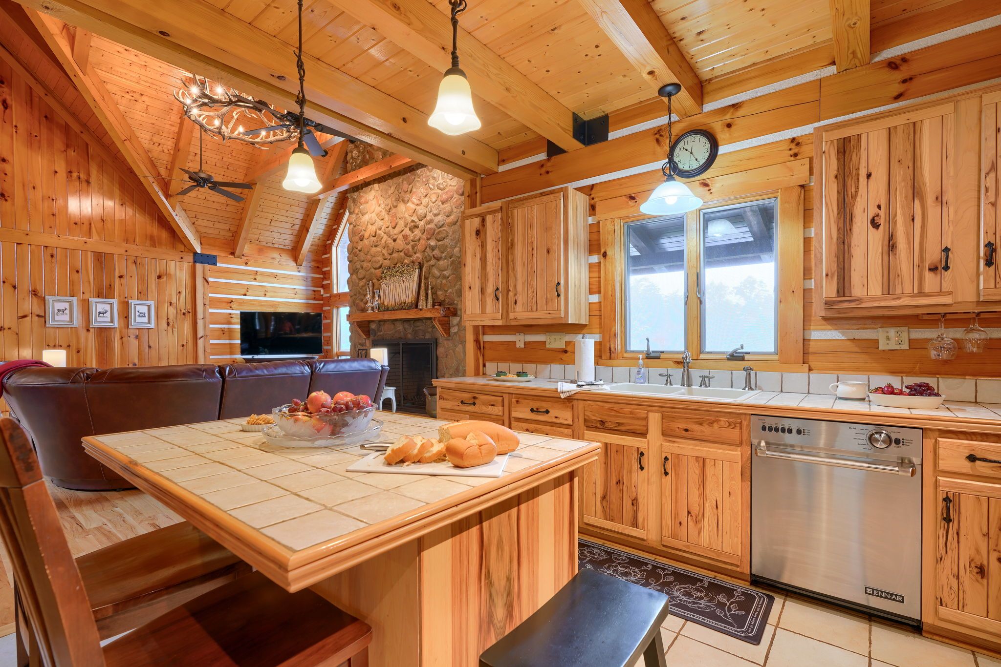 A wooden interior with a kitchen island, dining area, and a stone fireplace.