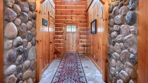 A wooden hallway with a stone wall, a red patterned rug, and a skylight. - Wow! Timber Ranch Lodge, 43 acres, Sleeps 12, Family and Pet Friendly!  (Logan)
