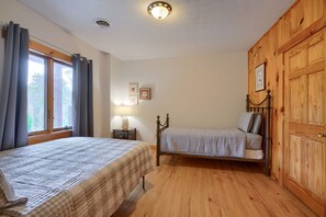 A room with two beds, a window with curtains, a lamp, and wooden walls. - Wow! Timber Ranch Lodge, 43 acres, Sleeps 12, Family and Pet Friendly!  (Logan)