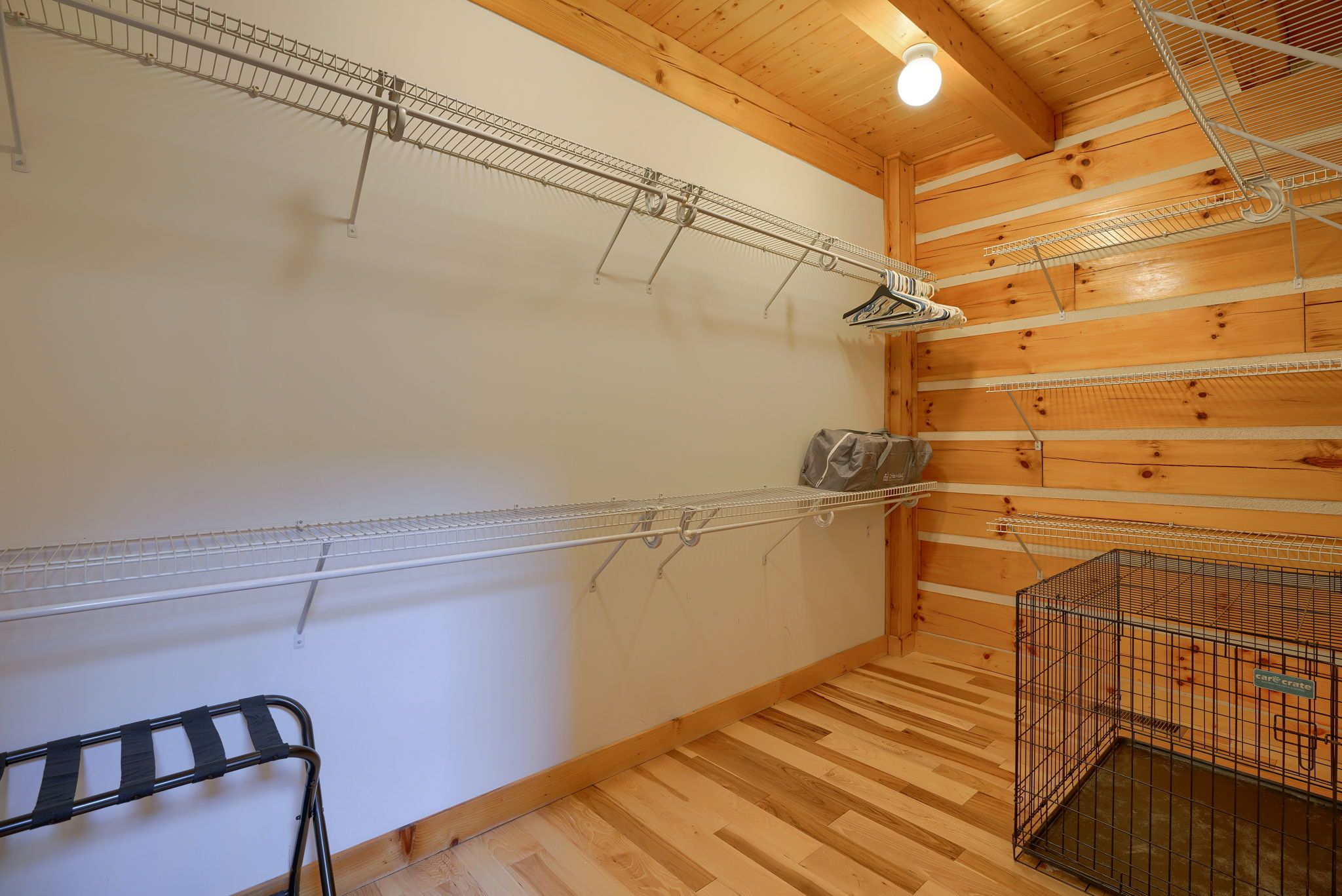 A room with wooden walls and floors, metal shelving units, and a metal cage.