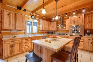 A kitchen with wooden cabinets, a central island, and modern appliances. - Wow! Timber Ranch Lodge, 43 acres, Sleeps 12, Family and Pet Friendly!  (Logan)