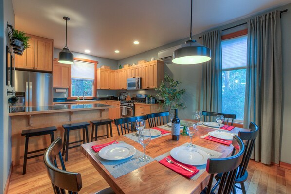 A modern kitchen with wooden cabinets, a central island, and a dining area set for six with a wooden table and chairs.