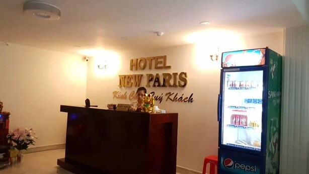 A reception desk with a sign reading "HOTEL NEW PARIS" and a Pepsi vending machine. - New Paris Hotel - by Bay Luxury (Ho Chi Minh City)